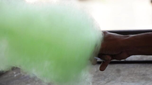 The seller is making gula kapas. Gula kapas is made from granulated sugar. Gula means sugar and kapas means cotton.