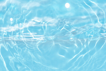 Blue water with ripples on the surface. Defocus blurred transparent blue colored clear calm water surface texture with splashes and bubbles. Water waves with shining pattern texture background.