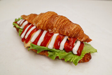 CROISSANT SANDWICH FILLED WITH TOMATOES, CUCUMBERS, Lettuce leaves and a sprinkling of tomato sauce and mayonnaise