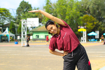 happy asian woman stretching hands in outdoor warm up before play basketball