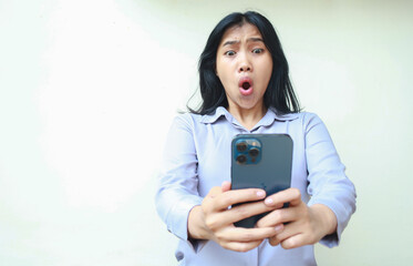 amazed asian young business woman using smartphone shocked with wow expression wearing formal shirt...