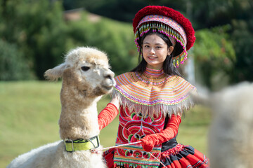 Smiling woman in colorful traditional attire poses with an alpaca against a scenic natural...