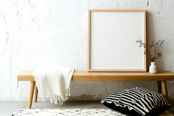 Minimalist home decor with empty frame and cozy textiles on wooden bench
