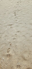 A long trail of footsteps on the sand. Shoes step on the sand. Traces of a lonely walk along the seaside
