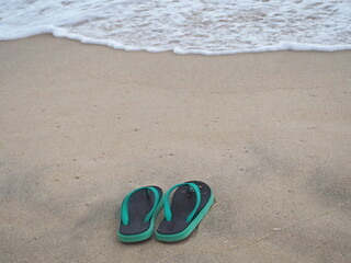 Flip flops placed on sandy beach. Tourists take off sponge shoes were removed and left in wet sand....