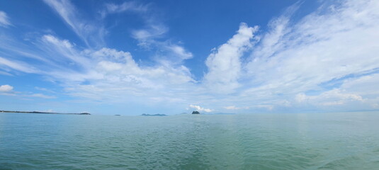 Atmosphere of the sky, sea, mountains in the distance. The endless sea, adorned with rhythmic waves, cloud clear blue sky horizon line calm empty sea. blue sky with white fluffy clouds and sea
