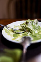 Spoon after eating green tea cake, pieces, and traces of green tea cake. Dirty plate
