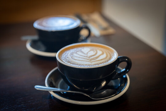 Two mugs of coffee. Latte art. Sit-in cafe  dining or restaurant casual style and lifestyle. Enjoy the morning with a coffee. Many coffee choices, such as cappuccino, latte, flat white, long black.