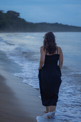 Woman Walking Along a Calm Beac by the ocean waves