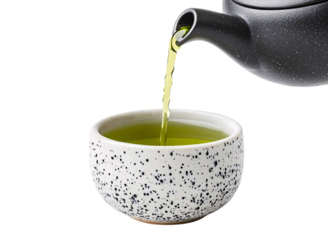 Steaming green tea poured from a black teapot into a spotty white cup capturing the essence of relaxation and culture