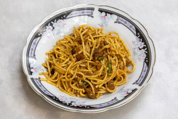 Homemade tasty beef chowmein noodles served in a white ceramic plate.