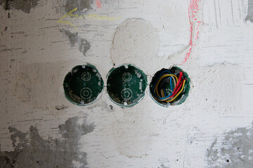 Green three wall boxes in a concrete wall. Installation of an electrical outlet in an apartment