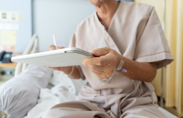Close up, Hand of patient is signing a consent form on digital tablet to receive treatment or use...