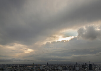 Fototapeta premium Aerial view of skyscrapers and dramatic sky before sunset. Beautiful clouds in the sky over large metropolitan city of bangkok, Copy space, Selective focus.