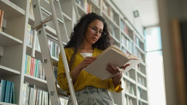Latina Indian Hispanic woman female student high school university learning girl studying library standing stairs librarian search book textbook pages college teacher learner bookstore buyer archive