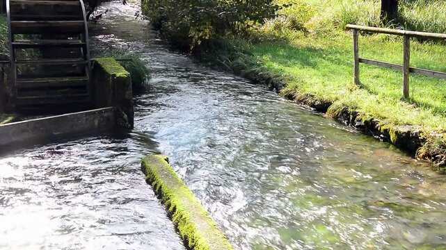 the sound of water flowing slowly near an old wheel of an old abandoned mill
