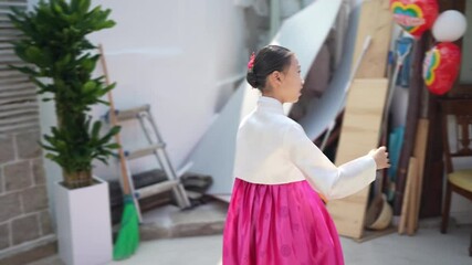 A 9-year-old Korean girl wearing a Hanbok is playing in a waterhole at a historical building in Seoul, South Korea, in the fall of October 2024.