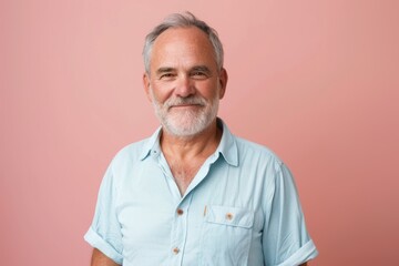 Obraz premium Calm Elegance: Mature Man with Grey Hair in Blue Shirt on Pink Background