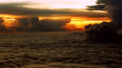Stunning aerial view of a dramatic sunset over a vast sea of ​​clouds. Photographed from inside the airplane window. with less blur, noise and darkness due to circumstances.