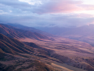 Drone view of landcape with mountains and hills at sunset. Beautiful clouds above mountains. Vivid...