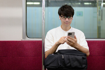 電車に乗る男性　スマホ　音楽