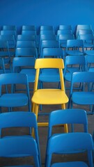 Obraz premium Yellow chair is in the middle of a row of blue chairs