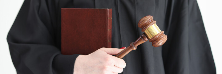 Judge in gown holds constitution and wooden gavel in studio