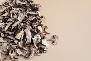 Close view from the top on a pile of pieces of dried mushrooms with copy space on beige background