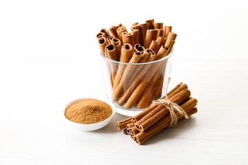 Dried Cinnamomum cassia and cinnamon powder on white wooden table.