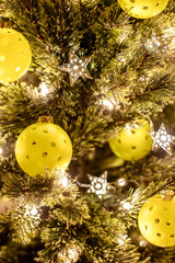 Close view of a Christmas tree with pickleballs as ornaments and shining lights and stars. Pickleball Christmas backdrop. Vertical orientation.