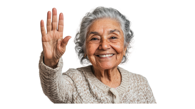 Smiling elderly woman waves hello with a warm expression while wearing a cozy sweater, showcasing joy and connection.