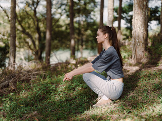 Thoughtful young woman sitting in a peaceful forest, enjoying nature while contemplating, dressed...