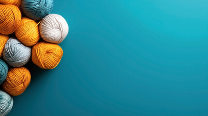 Colorful balls of yarn arranged on the left side of a turquoise background, featuring shades of blue, orange, and white yarn.