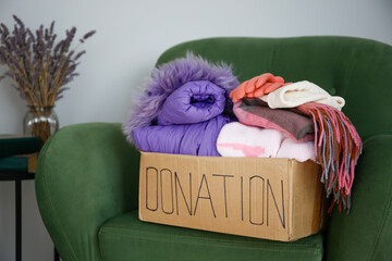 Donation box with clothes on the armchair in the living room.