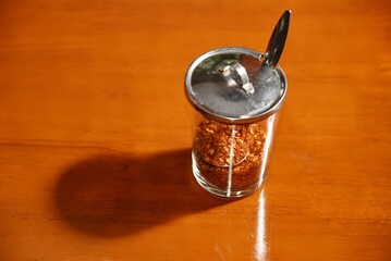 Cayenne pepper in a condiment glass on wooden table