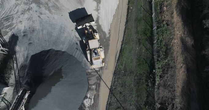 Stone crusher plant, loader transporting gravel in a bucket, aerial top view, tracking shot.