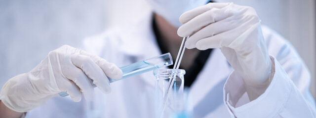 Close-up scientist pouring blue liquid into test tube beaker flask equipment pipette working...