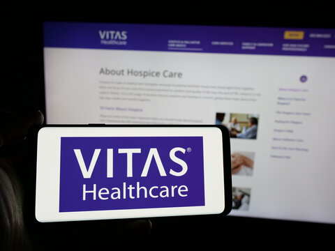 Stuttgart, Germany - 10-18-2024: Person holding smartphone with logo of US health care company VITAS Healthcare on screen in front of website. Focus on phone display.