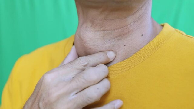 Thyroid gland inflammation at neck, goiter, throat cancer, sore throat and cough, man with neck pain on green, neck health problems concept