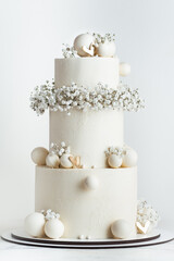 Beautiful three-tier wedding cake with white chocolate frosting decorated with chocolate spheres...
