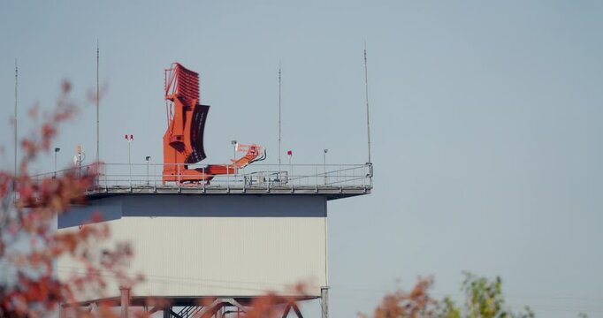 A striking shot of a red airport satellite spinning in place, capturing the intricate details of its design and technology. The vivid color contrasts against the backdrop.
