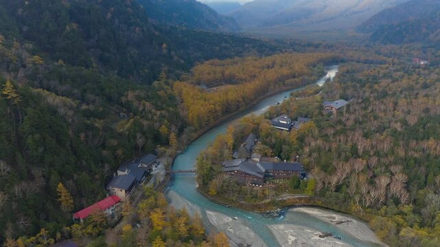 Aerial drone footage along river and Kappa bridge in Kamikochi Japan in Autumn season. Japanese nature travel destination tourist attraction national park scene.
