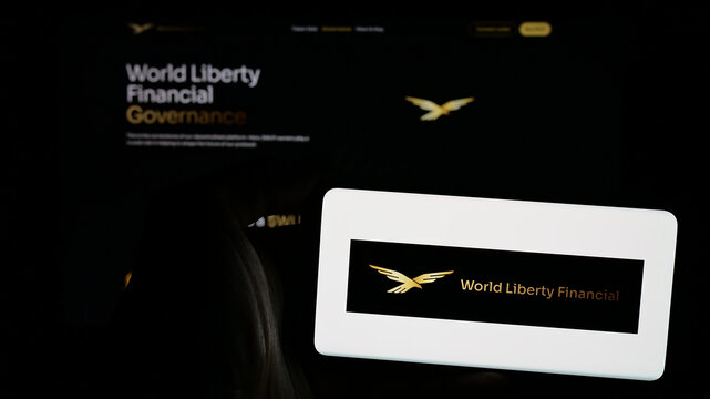 Stuttgart, Germany - 10-22-2024: Person holding mobile phone with logo of US crypto company World Liberty Financial Inc. on screen in front of web page. Focus on phone display.
