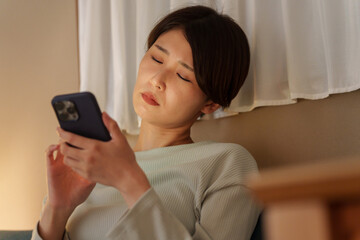 スマホを使いながら寝落ちする女性