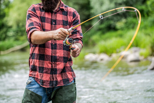 Man fishing on a mountain river with a spinning using fishing in plaid shirt. Fishing. Fisherman. Fishing rod lake fisherman men sport. Fisherman with rod fishing on the lake