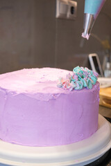 Pink cake being decorated with frosting