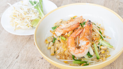 Thai stir-fried noodles (Pad Thai) and shrimp on a white plate.
