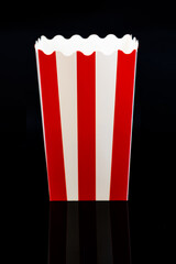 Vertical image of cardboard popcorn bucket reflected on a black background, cinema and popcorn concept