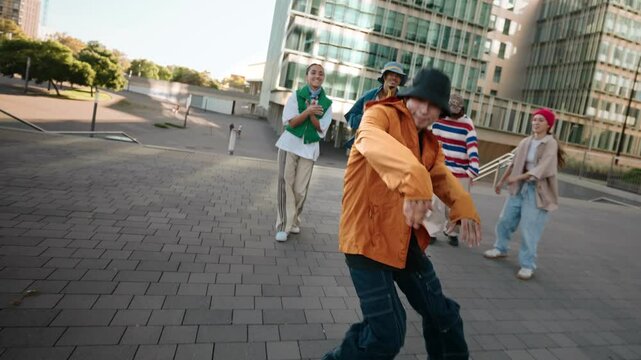 Asian man dancing modern urban street free style dance with energy together with group of friends in the city