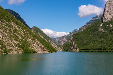 Scenic ferry boat tour on Lake Koman reservoir on Drin river surrounded by forested steep hills, cliffs and majestic rugged mountain ranges of Albanian Alps. Panoramic view along Albanian Fjords. Awe